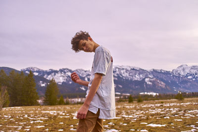 Portrait of young man with head cocked standing on field during winter