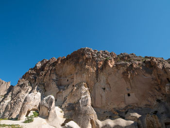 Low angle view of rocks against clear blue sky