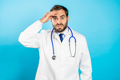 Young man standing against blue background