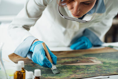 Restoring old oil painting, conservator removing varnish from an oil painting