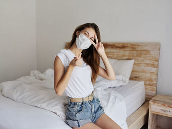 Young woman sitting on bed at home