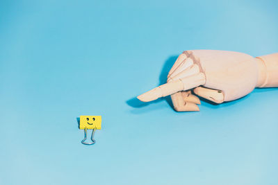 Close-up of hand holding toy against blue background