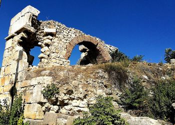 Low angle view of old ruins against blue sky