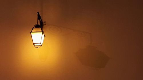 Illuminated light bulb hanging on wall