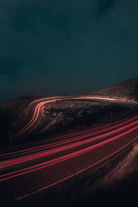 Light trails on road against sky at night