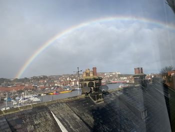 Rainbow over buildings in city against sky