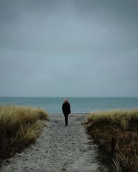 Rear view of woman on beach against sky