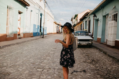 Woman standing on street against buildings in city