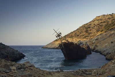 Shipwreck against a scenic view of sea against clear sky