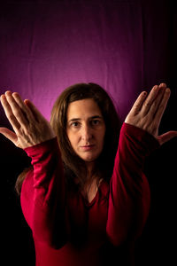 Portrait of young woman standing against black background