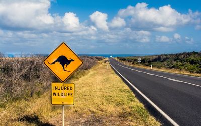 Signboard by road at great ocean road against sky 