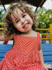 Little girl playing on the playground looking and laughing at camera.