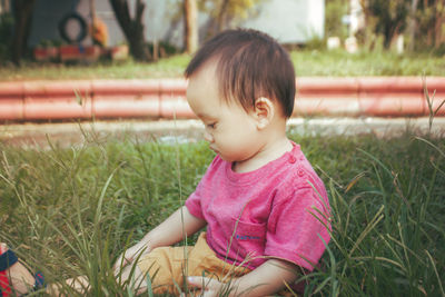 Cute baby boy sitting on the grass in the garden