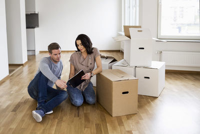 Full length of couple reading brochure into their new house