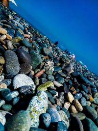 Close-up of stones on beach against clear blue sky