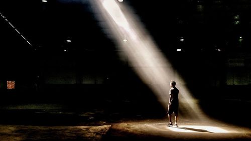 Woman walking on illuminated footpath at night