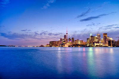 City at waterfront against blue sky