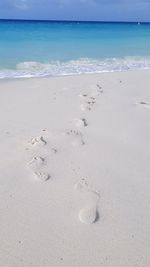 Footprints on sand at beach against sky