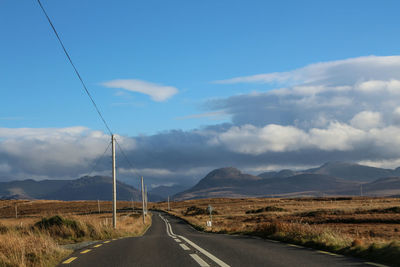 Road leading towards mountains against sky