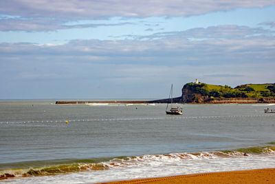 Sailboat on sea shore against sky