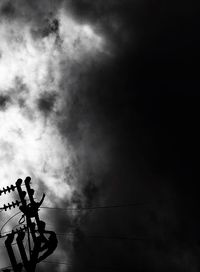 Low angle view of silhouette bird perching on pole against sky