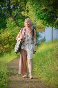 Portrait of smiling woman in hijab standing on footpath