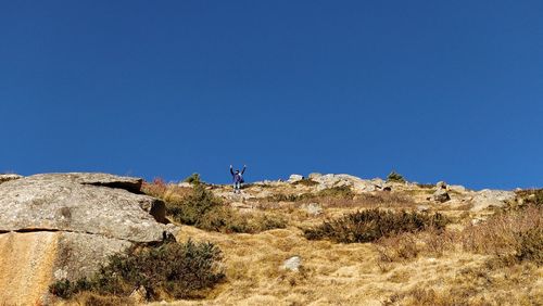 Low angle view of rocks against clear blue sky