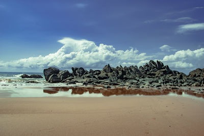 Scenic view of rocks on beach against sky