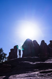 People on rocks against clear blue sky