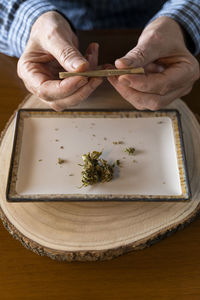 Senior man at home rolling marihuana joint