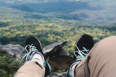 Low section of man wearing shoes on rock