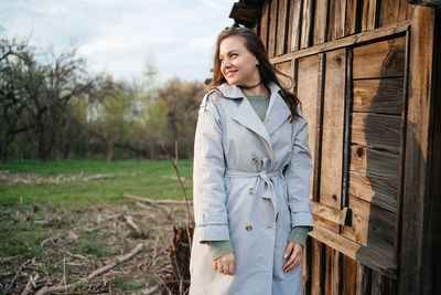 Girl with long hair in a grey trench coat outdoors in spring