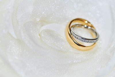 Close-up of wedding rings on white glittering textile