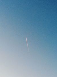 Low angle view of vapor trail against clear blue sky