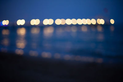 Defocused image of illuminated lights in sea at night