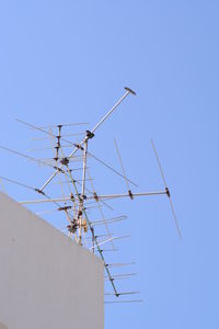 Low angle view of telephone pole against clear blue sky