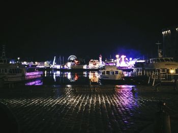 Boats moored at harbor against clear sky at night