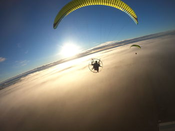 Low angle view of person paragliding against clouds