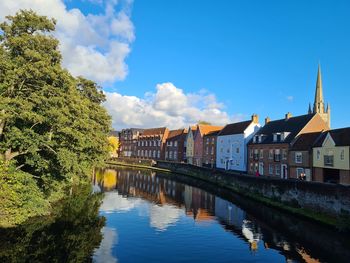 Bridge over river by buildings against blue sky