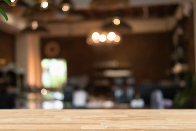 Defocused image of illuminated lights on table at cafe