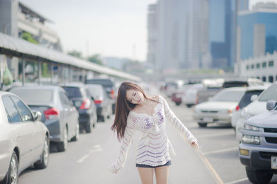 Beautiful young woman standing at parking lot