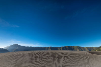 Scenic view of desert against blue sky