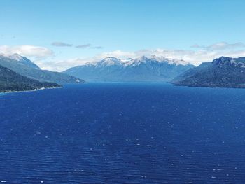 Scenic view of sea and mountains against blue sky