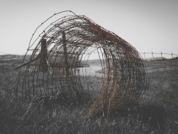 Damaged fence on field against clear sky