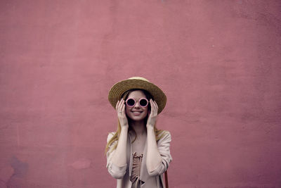 Portrait of smiling woman standing against pink wall