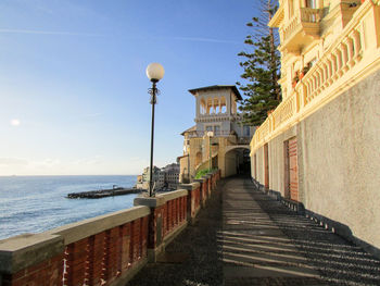 Street amidst buildings and sea against sky