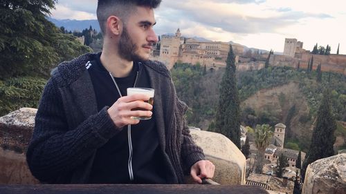 Young man with beer glass looking away