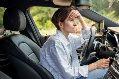 Stressed middle aged woman driving car having problems on road looking ahead.