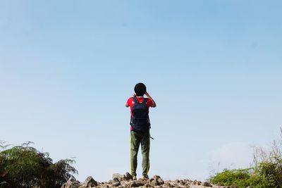 Rear view of man with backpack standing against clear sky