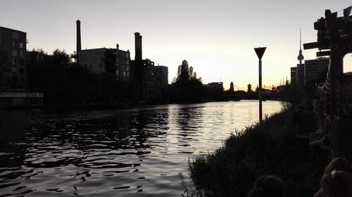 River in city against sky at sunset